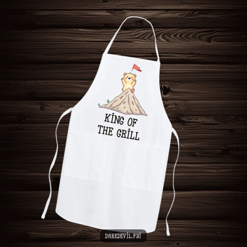 Funny bear apron showing a whimsical bear triumphantly planting a flag on a tiny mountain peak, ready for culinary victories.